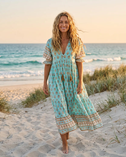 Woman wearing the Juno Floral V-Neck Maxi Dress in aqua blue on an Australian beach at golden hour