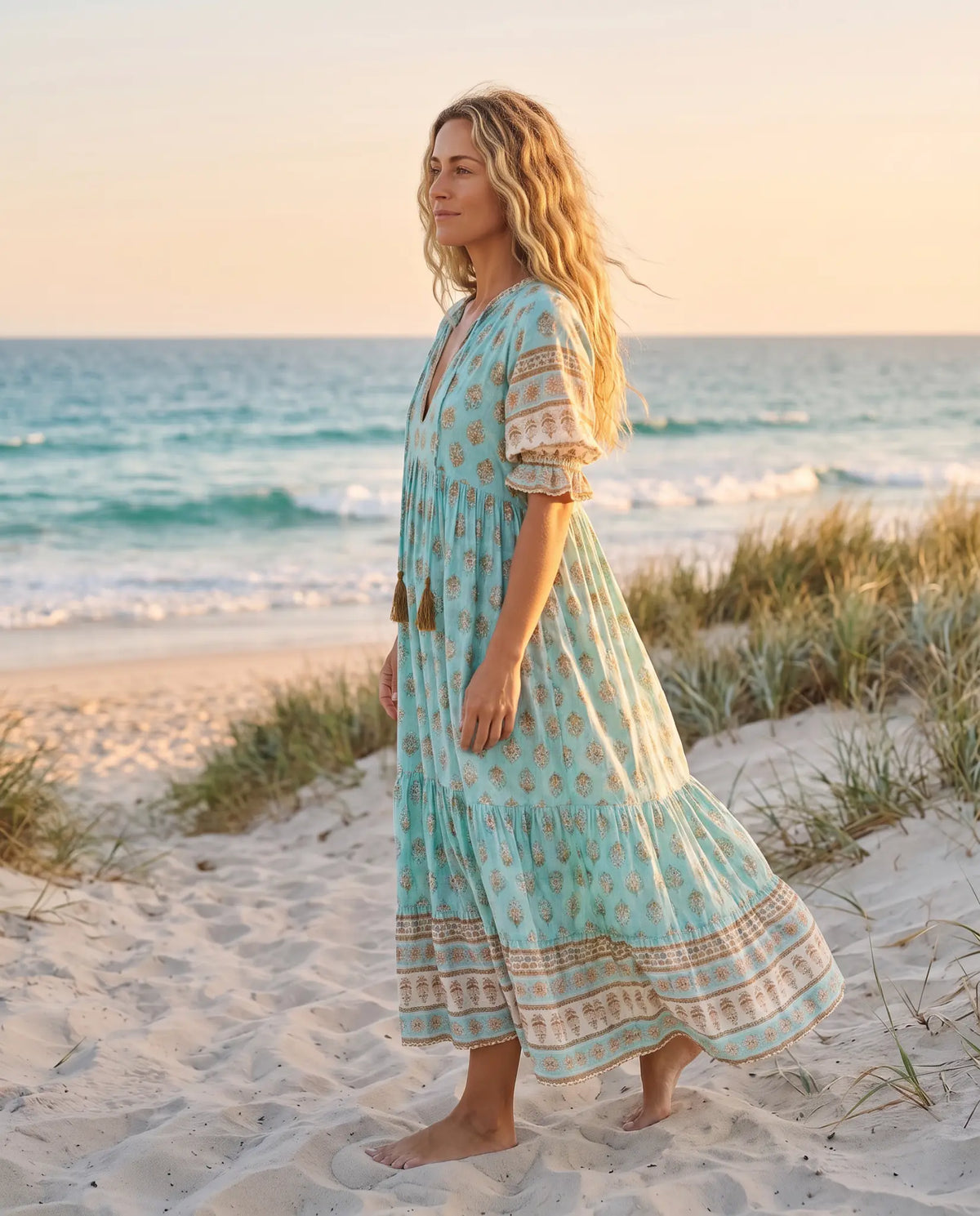 Side view of the Juno Floral V-Neck Maxi Dress in aqua blue on an Australian beach at golden hour