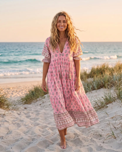 Woman wearing the Juno Floral V-Neck Maxi Dress in rose pink on an Australian beach at golden hour