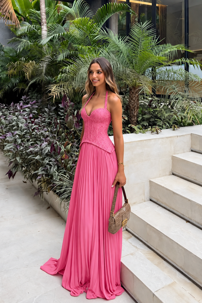 Enid Pleated Corset Maxi Dress – Pink worn beside tropical greenery and pale stone steps